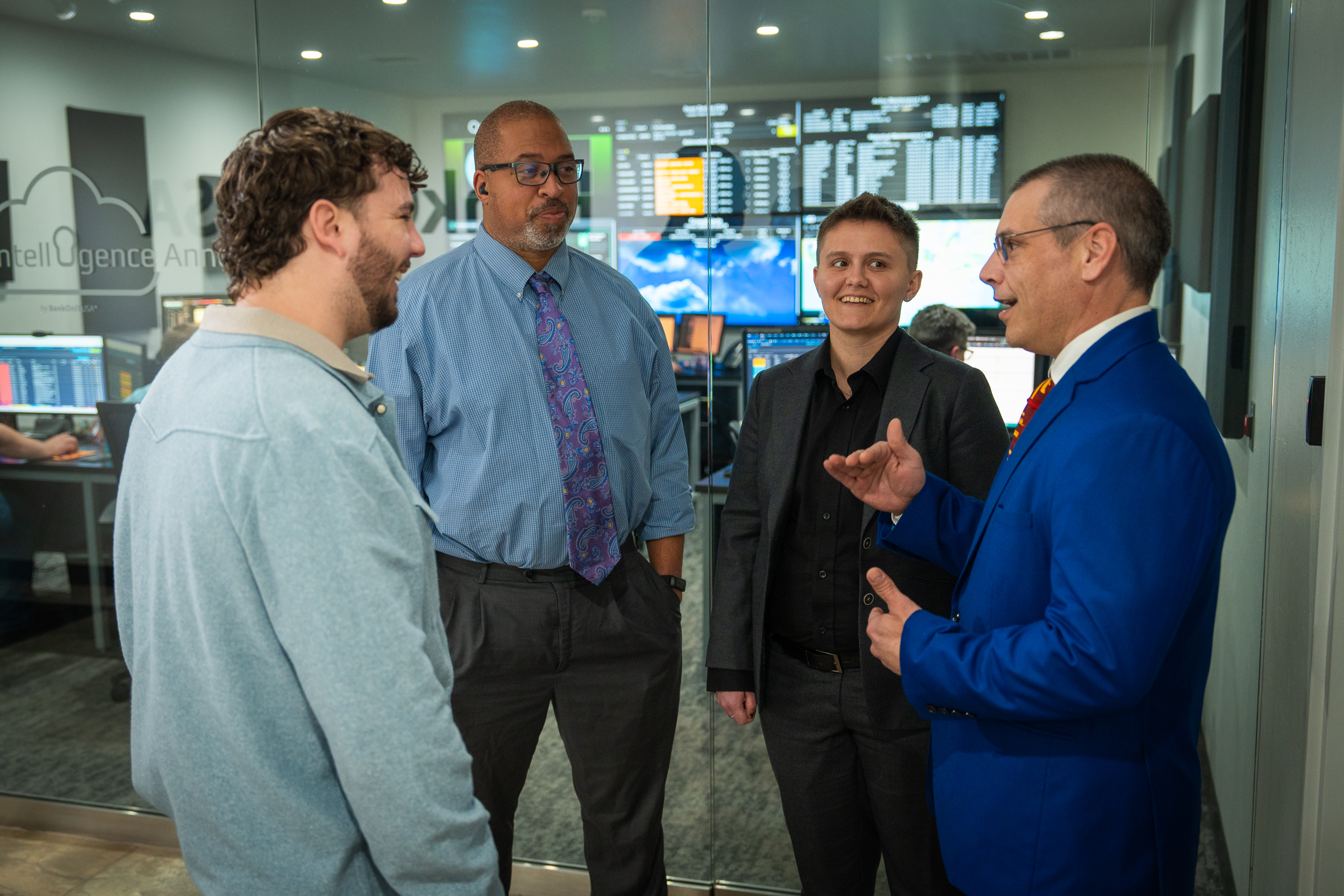 Group of three people focused on a person talking in an office setting.