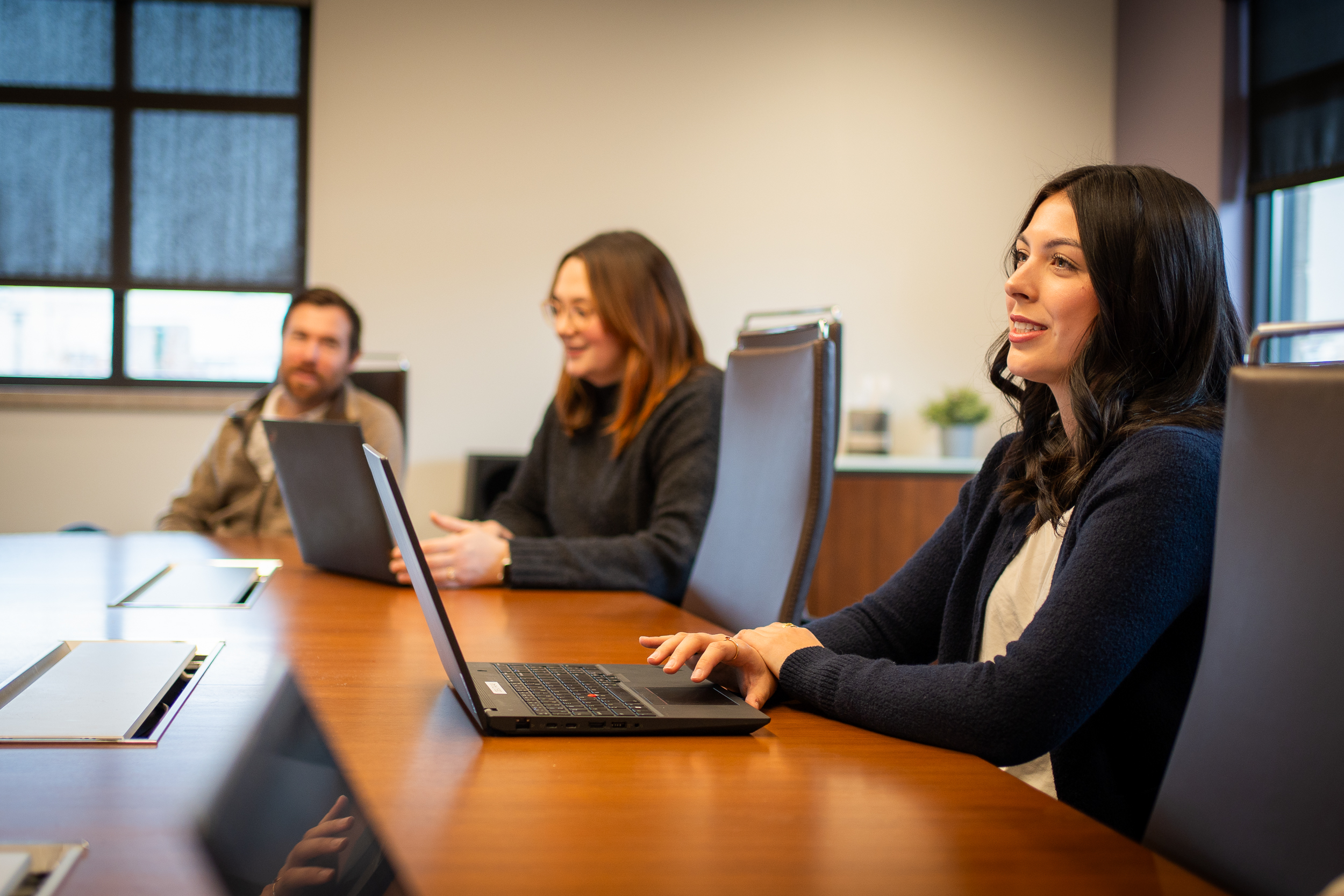 Group of people sitting at a conference table with their laptops.